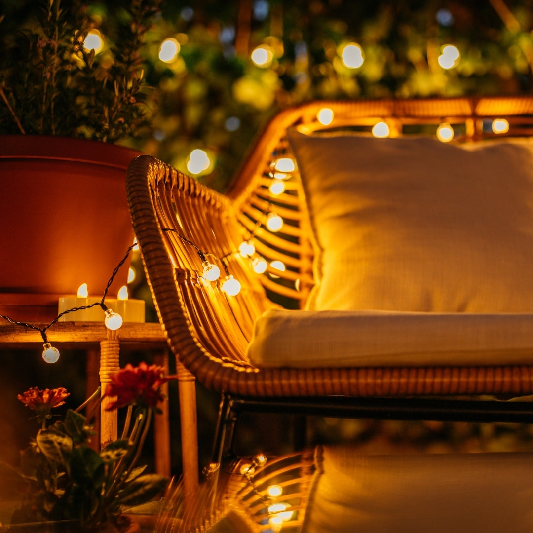 Wicker chair with cushions under fairy lights in a cozy outdoor setting