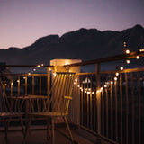 Balcony with fairy lights and chairs at night with mountains in the background