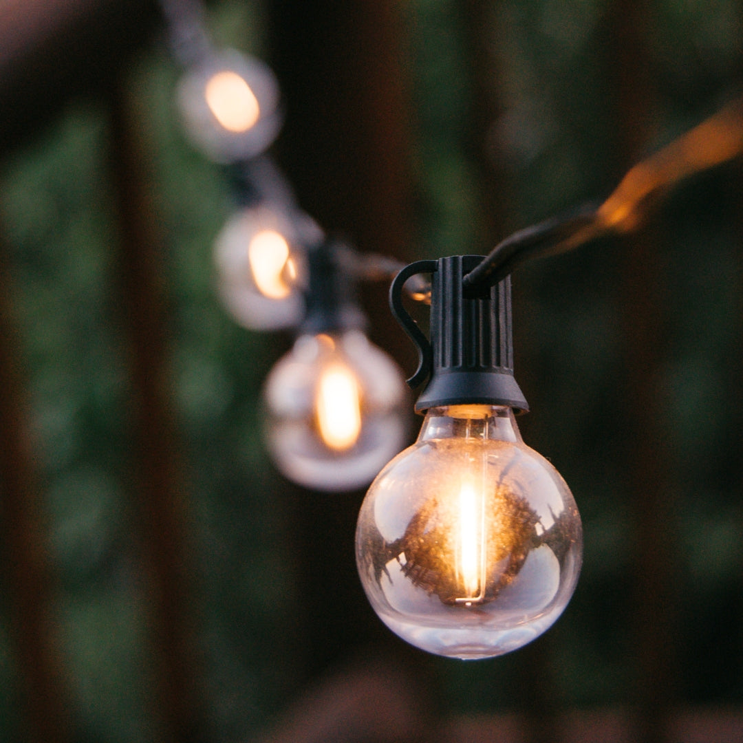 Solar Classic String Lights with 25 warm white G40 globe bulbs on black cable glowing in a styled South African outdoor space powered by solar energy