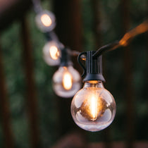Solar Classic String Lights with 25 warm white G40 globe bulbs on black cable glowing in a styled South African outdoor space powered by solar energy