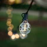 Solar G40 globe LED replacement bulbs glowing warm white on black string lights strung beneath an outdoor tent ceiling