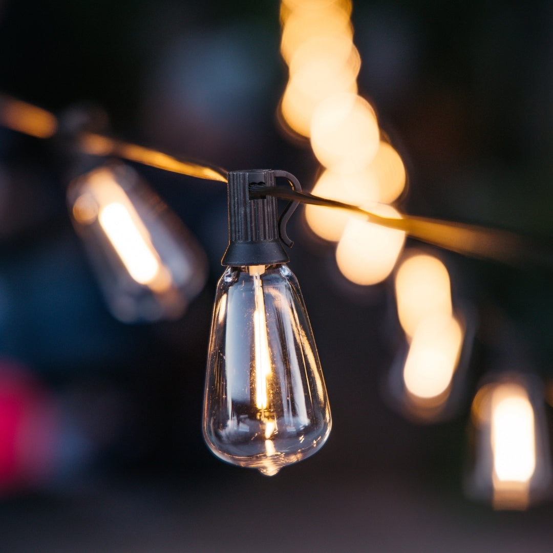 Solar ST38 vintage LED replacement bulbs glowing warm white on black solar string lights strung outdoors