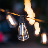 Solar ST38 vintage LED replacement bulbs glowing warm white on black solar string lights strung outdoors