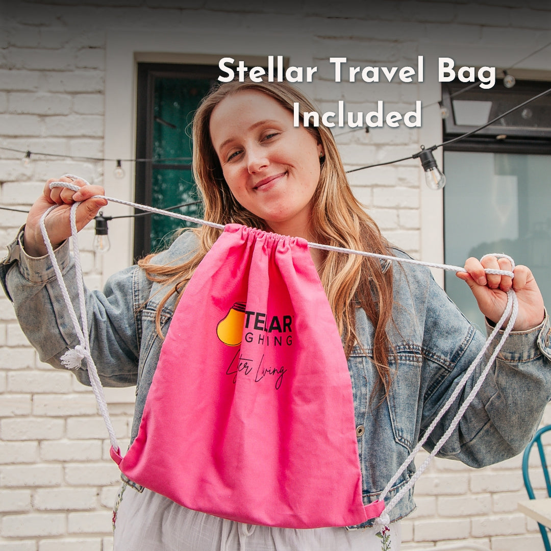 Woman holding a pink drawstring bag included with solar string lights with Stellar Lighting text, standing outdoors.