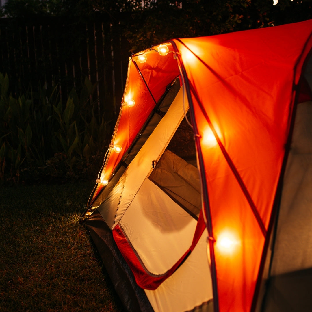 Solar string lights with G40 globe bulbs strung along a camping tent at night with warm amber glow
