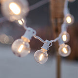 Close-up of G40 globe LED bulbs glowing on white cable at dusk with warm white light