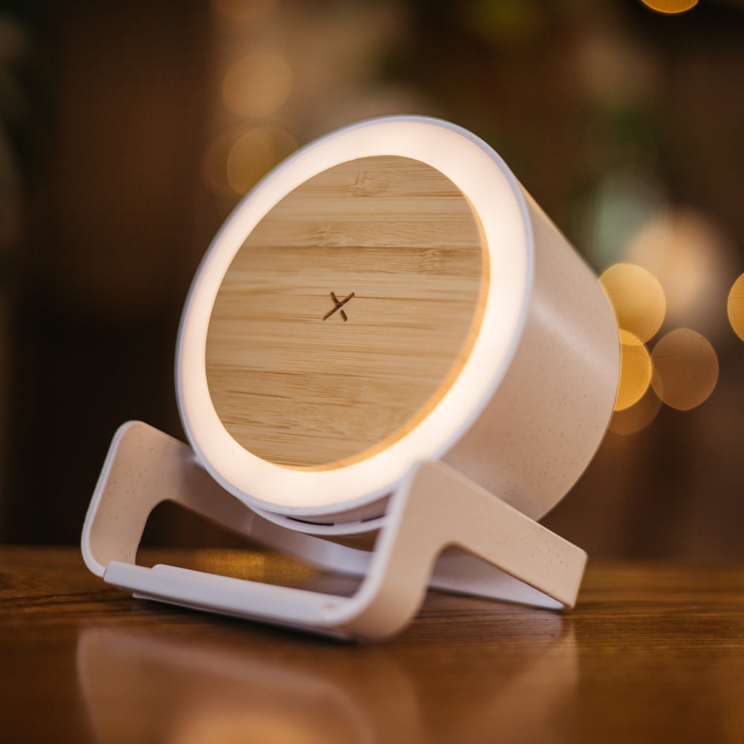 Bamboo speaker wireless charger with glowing LED ring light on a wooden surface with warm bokeh