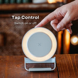 Hand tapping the LED ring light surface on white speaker wireless charger to switch it on with tap control callout