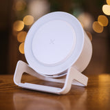 White speaker wireless charger with glowing LED ring light on a wooden surface with warm bokeh in the background