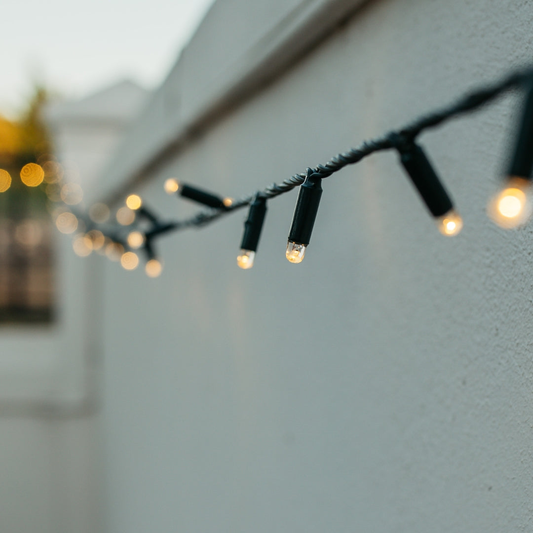 Styled outdoor garden lit with Ultimate Dark Green Fairy Lights of warm white LED on dark green cable blending into foliage