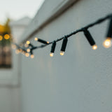 Styled outdoor garden lit with Ultimate Dark Green Fairy Lights of warm white LED on dark green cable blending into foliage