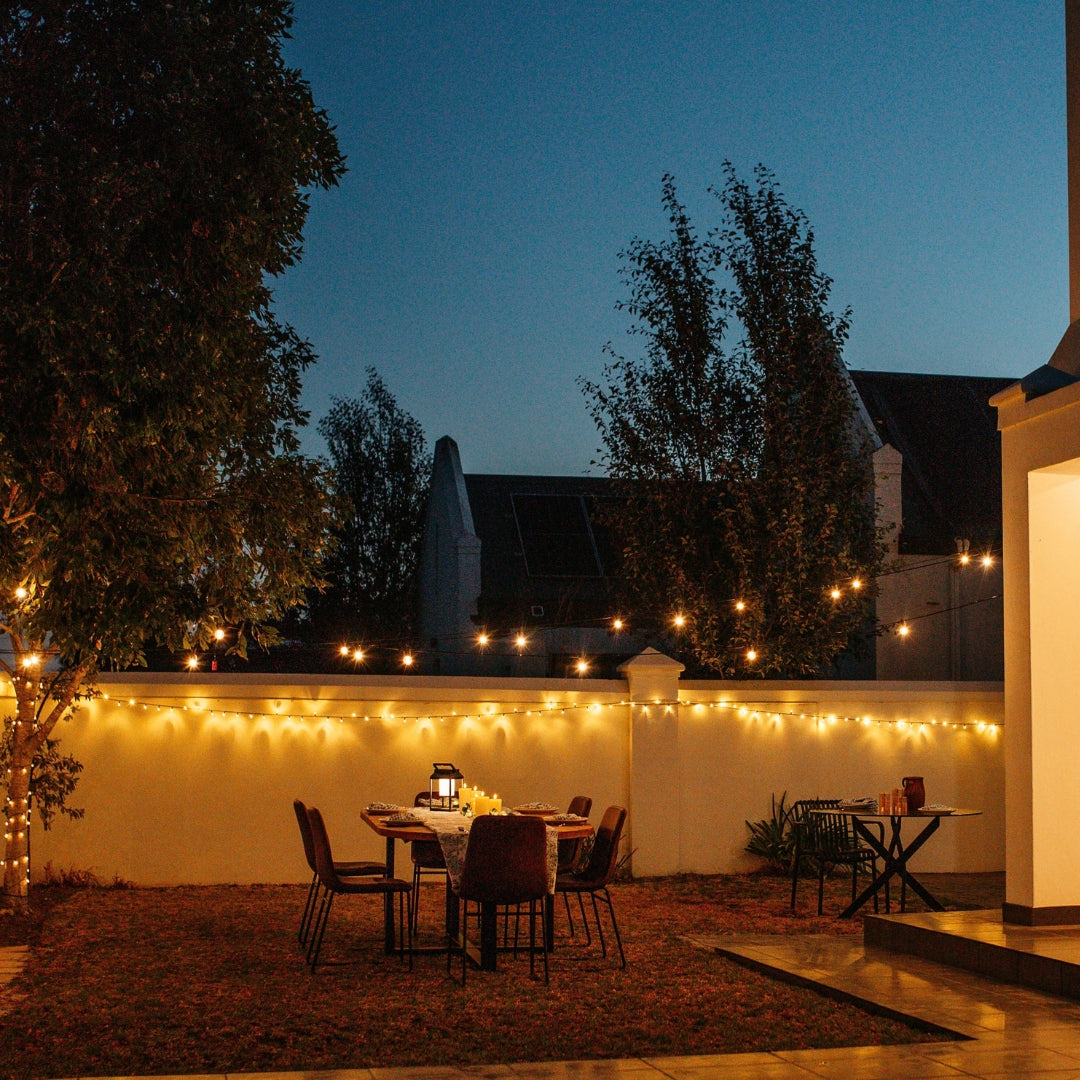 Ultimate Dark Green Fairy Lights with warm white LEDs on dark green cable woven through garden hedges and foliage creating a warm continuous shimmer at night