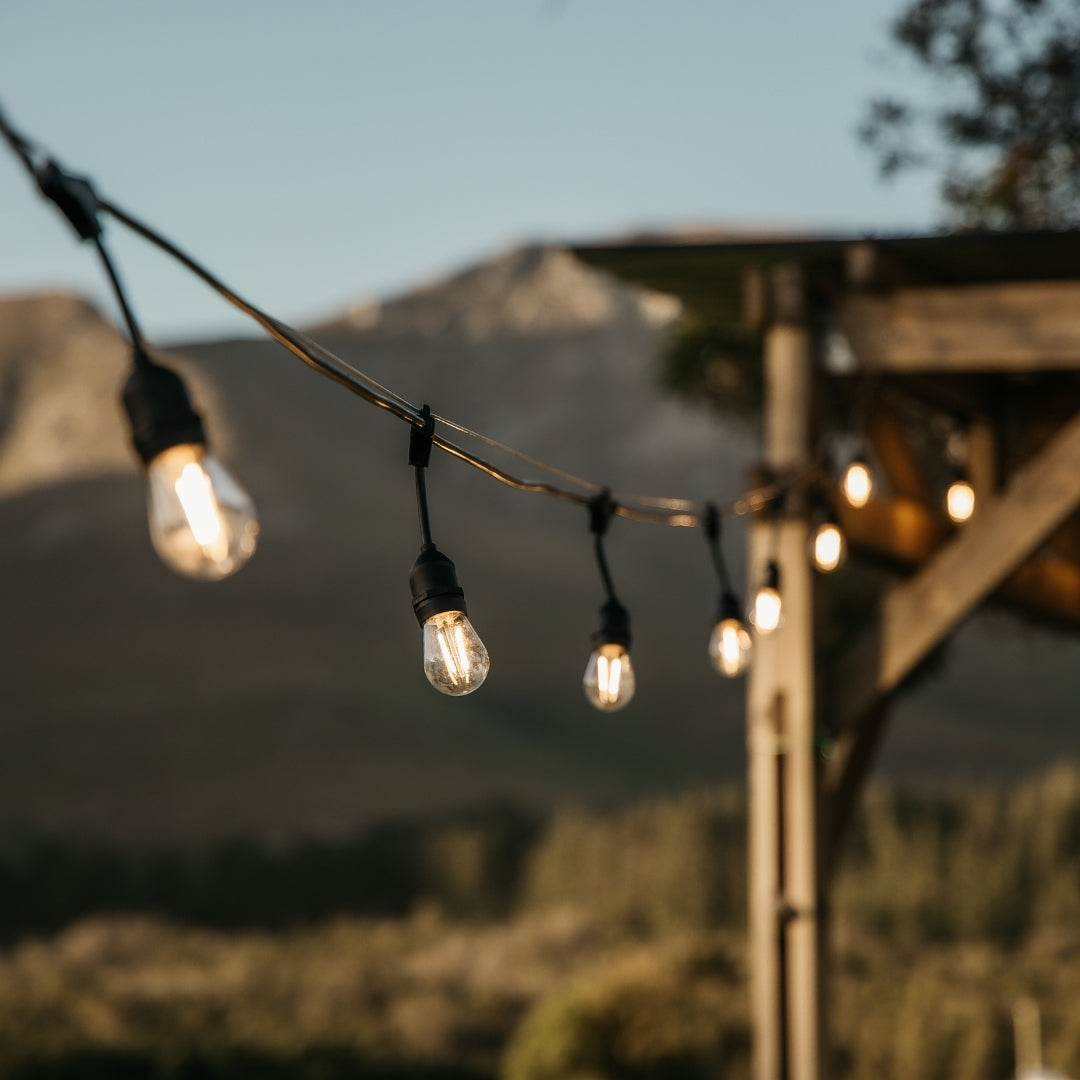 String lights with a mountainous background and a pergola.