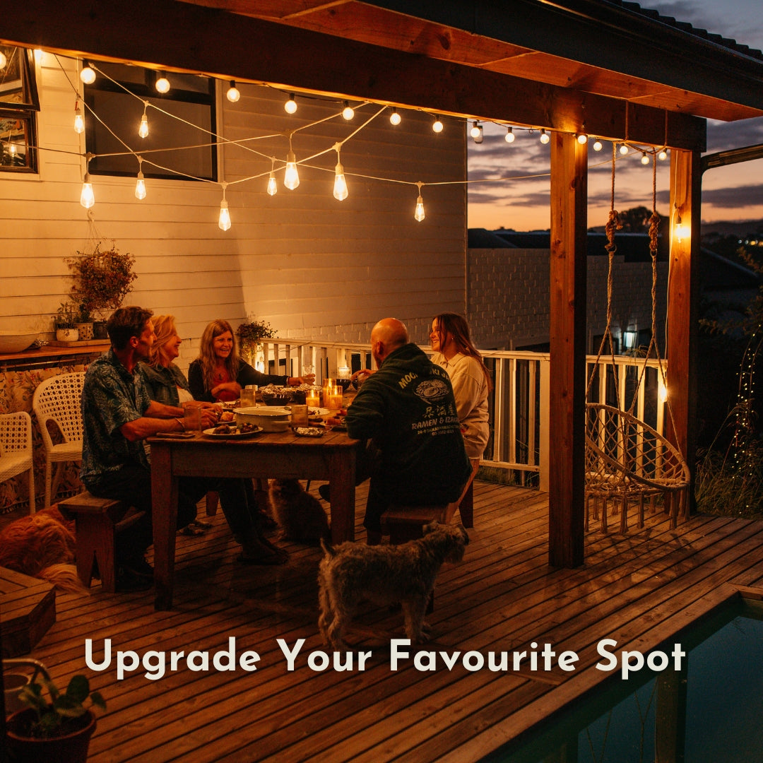 Ultimate White Drop String Lights suspended on individual drop wires across a South African garden at night with outdoor dining table set for dinner, braai area, and pool reflecting warm light in the foreground