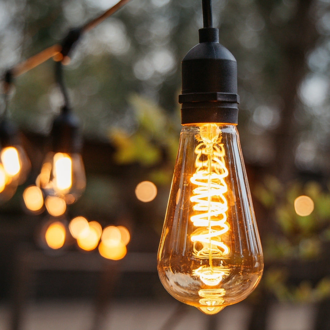 ST64 vintage LED bulb with golden spiral filament glowing warm amber in an interior setting