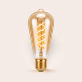 Single ST64 vintage LED bulb with golden spiral filament and amber tinted glass on a light background