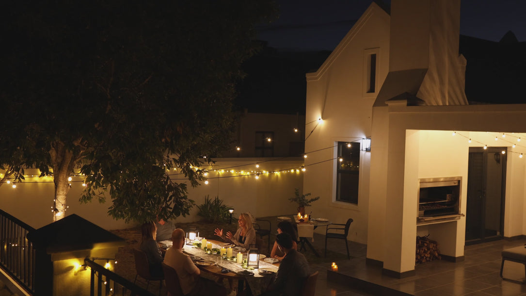 Video of string lights, fairy lights, and lanterns to create warm ambience during an outdoor evening dinner.