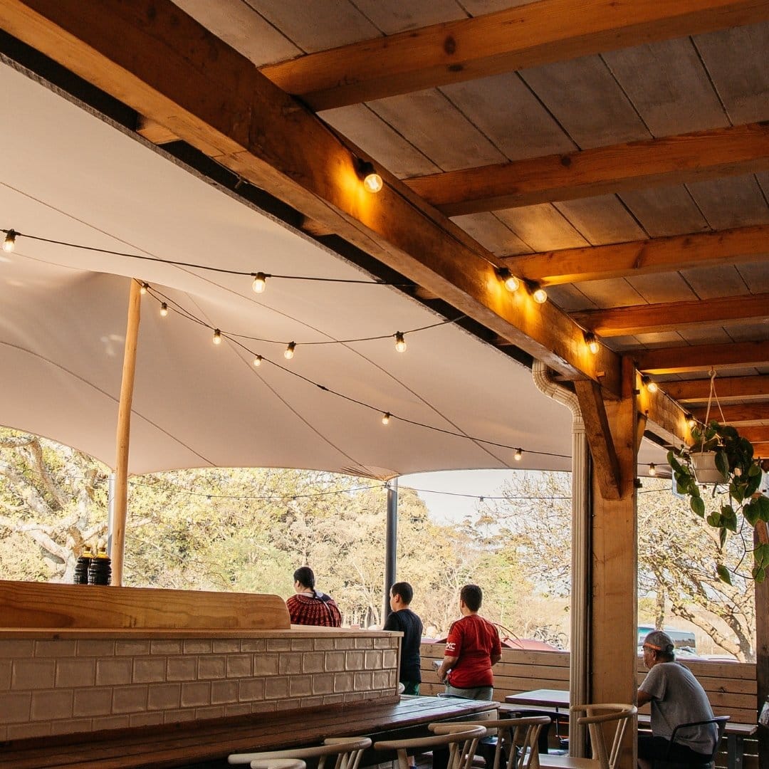 Retro-style festoon bulbs draped between pergolas at Peregrine outdoor seating