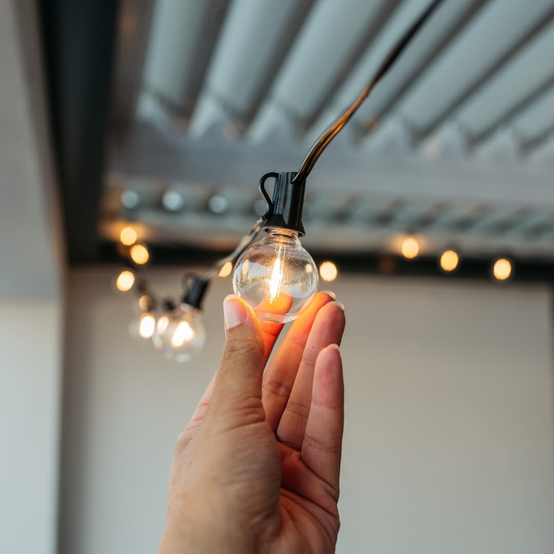 Outdoor black string lights with 25 warm LED bulbs creating a soft glow over a patio at night