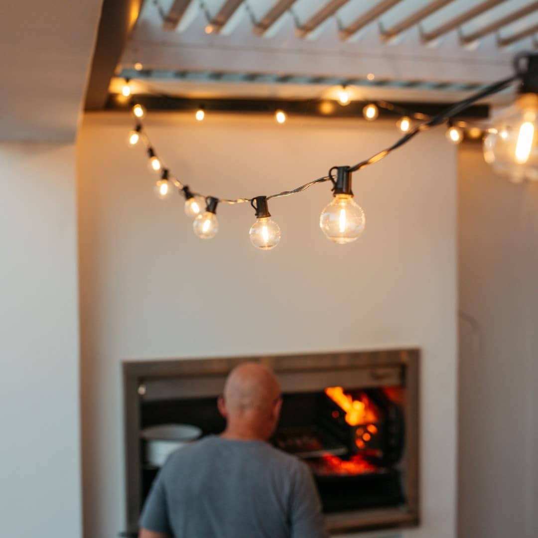Outdoor black string lights with 25 warm LED bulbs creating a soft glow over a patio at night