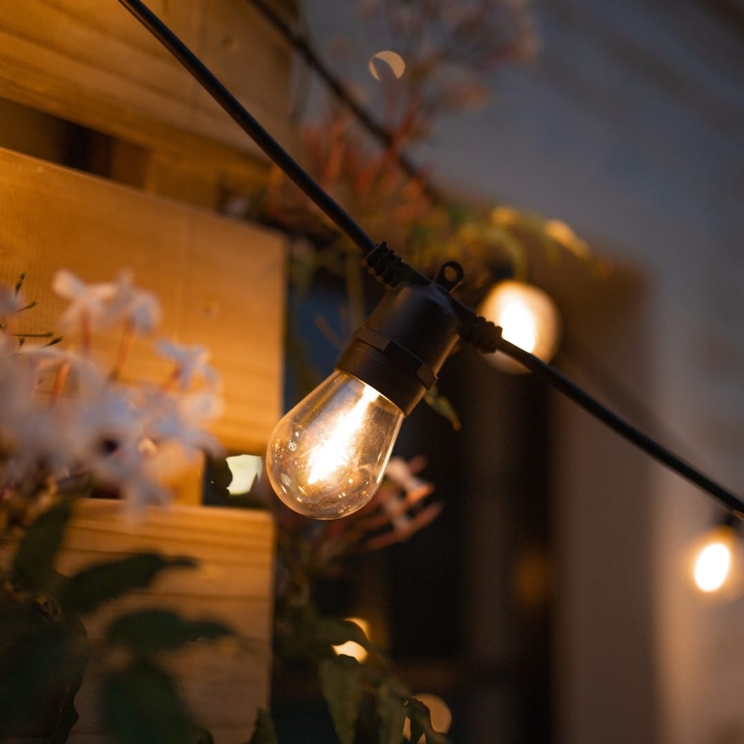 Warm white solar festoon string lights creating a cosy outdoor glow.