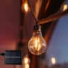 Solar powered cotton string lights with 10 warm LED bulbs hanging in a cosy covered patio setting.