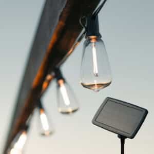 Solar-powered vintage LED string lights glowing at dusk in an outdoor setup