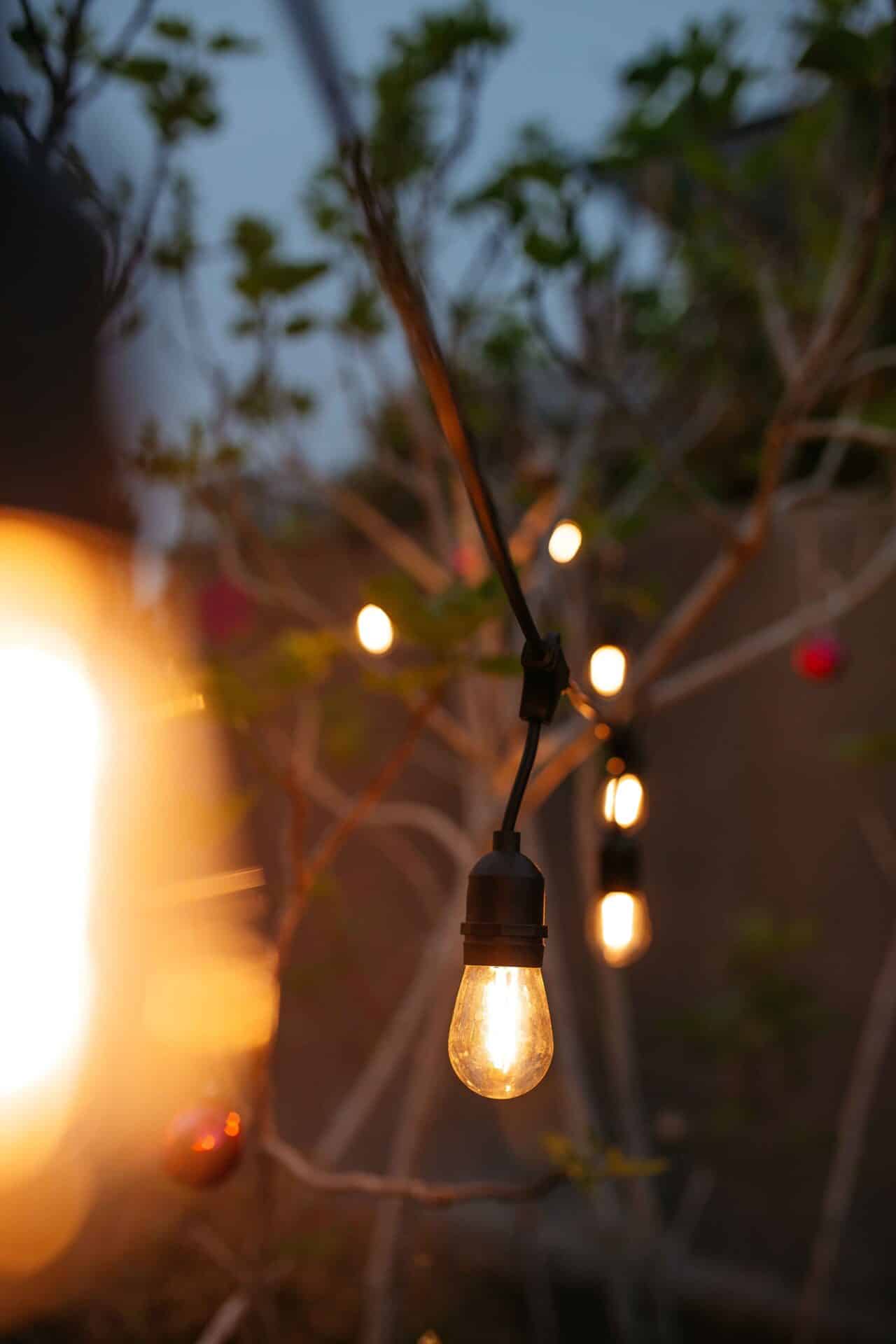 Warm white 10m plug-in festoon string lights by Stellar Lighting hanging over an outdoor dining area in South Africa.