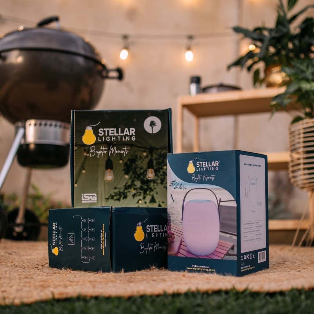 Outdoor string lights and speaker lantern illuminating a braai area at dusk.