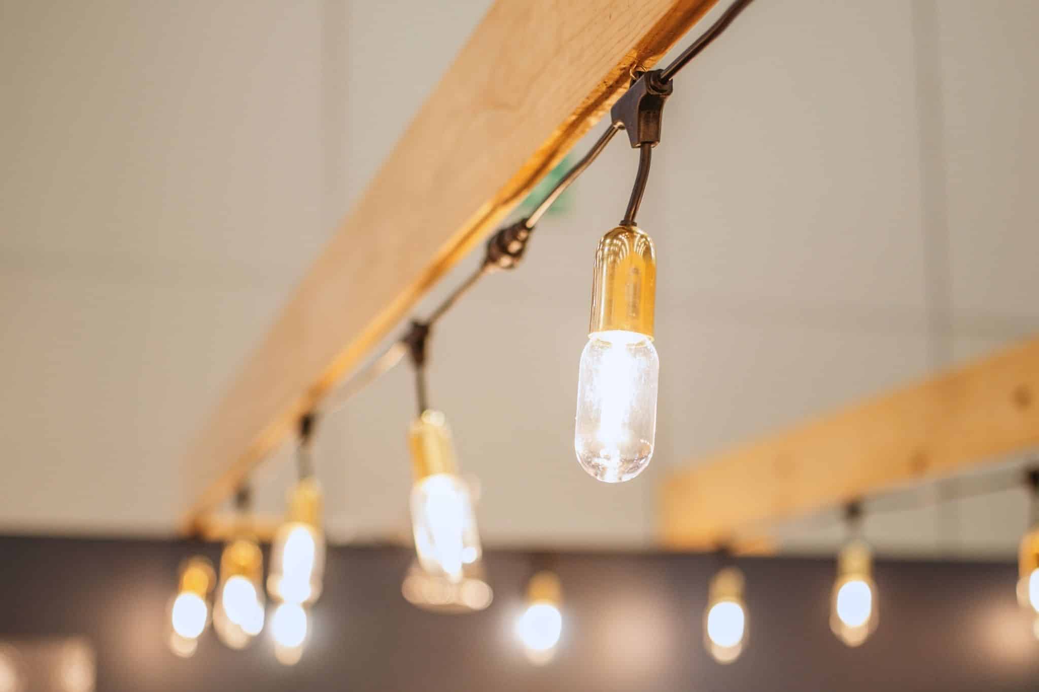 Gold drop string lights by Stellar Lighting hung under a pergola at Decorex.