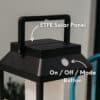 Black solar LED lantern mounted on outdoor wall with soft glow