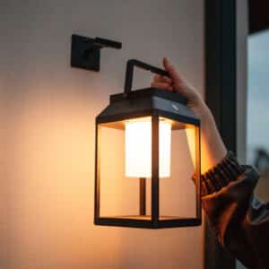 Black solar LED lantern mounted on outdoor wall with soft glow