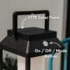 Black solar LED lantern mounted on outdoor wall with soft glow