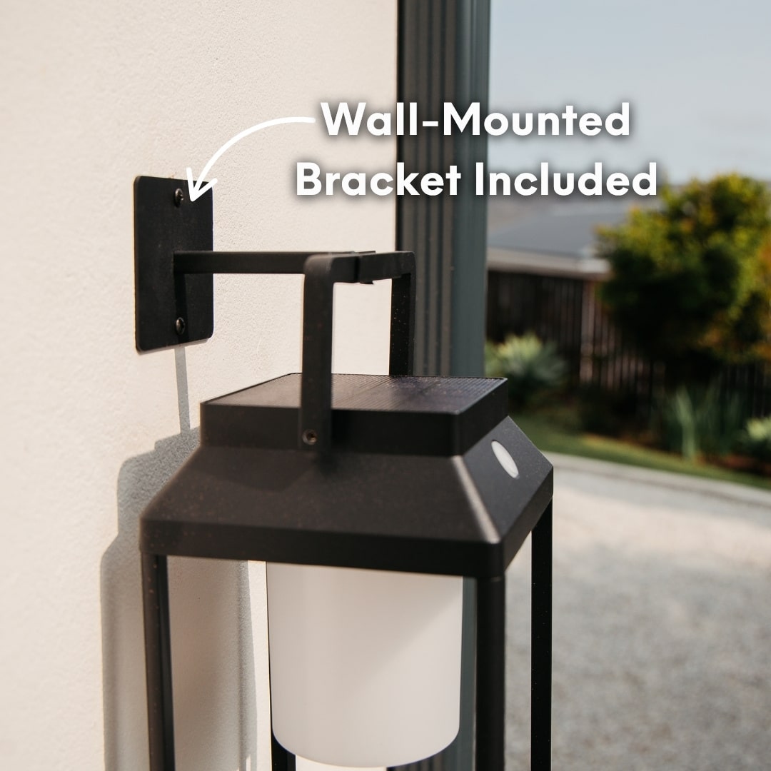 Black solar LED lantern mounted on outdoor wall with soft glow