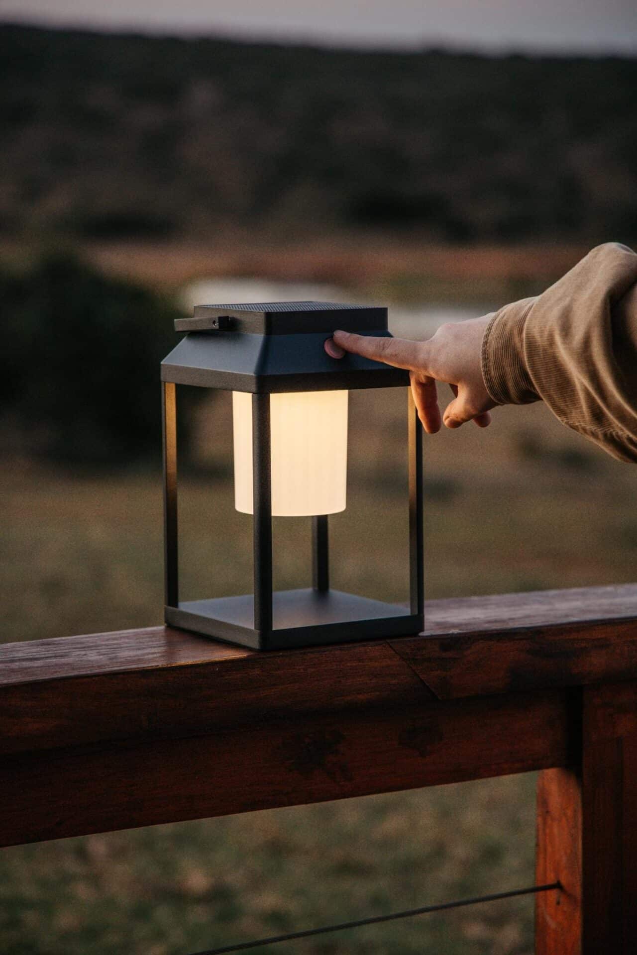 Black solar LED lantern mounted on outdoor wall with soft glow