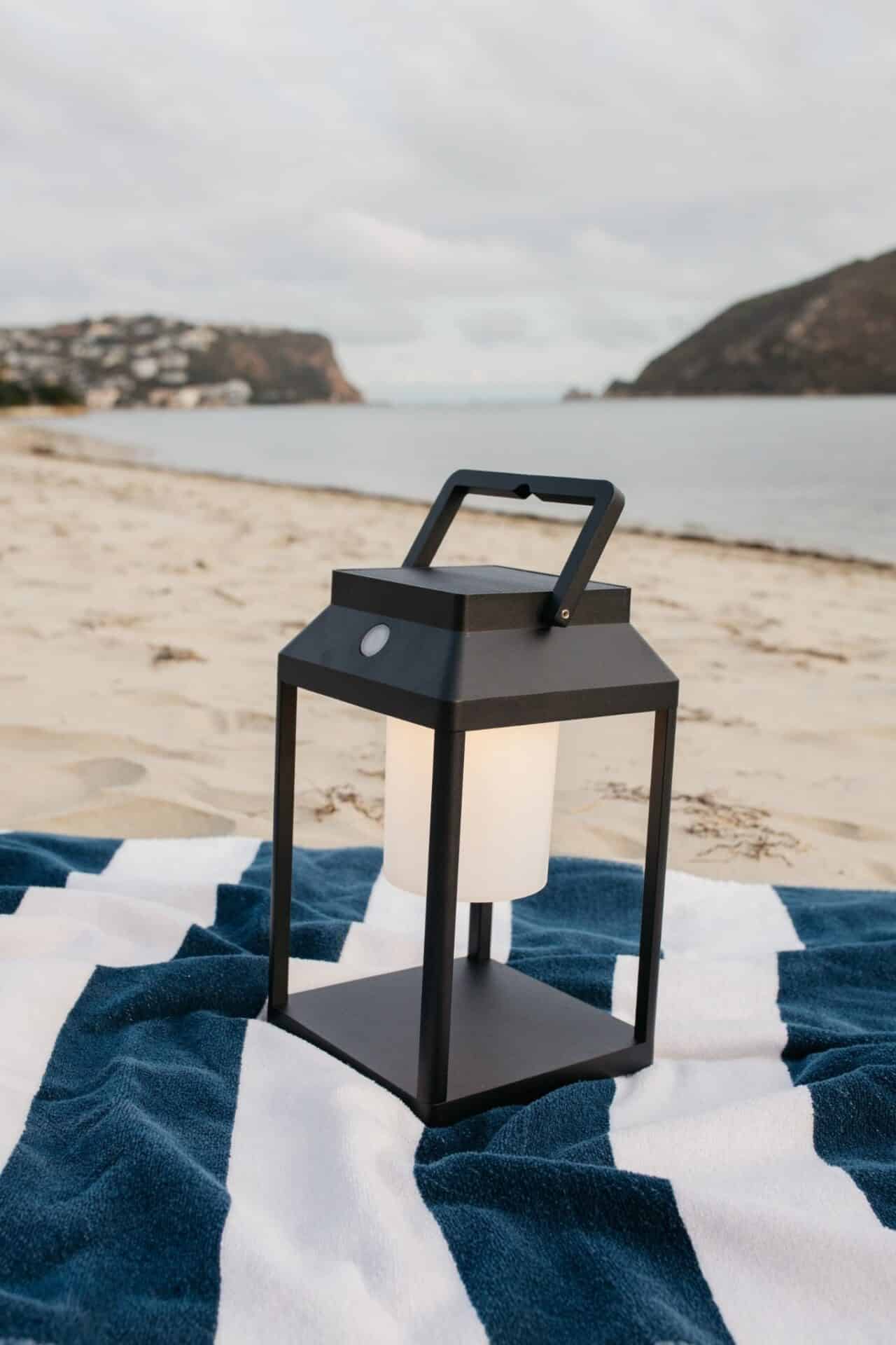 Black solar LED lantern mounted on outdoor wall with soft glow