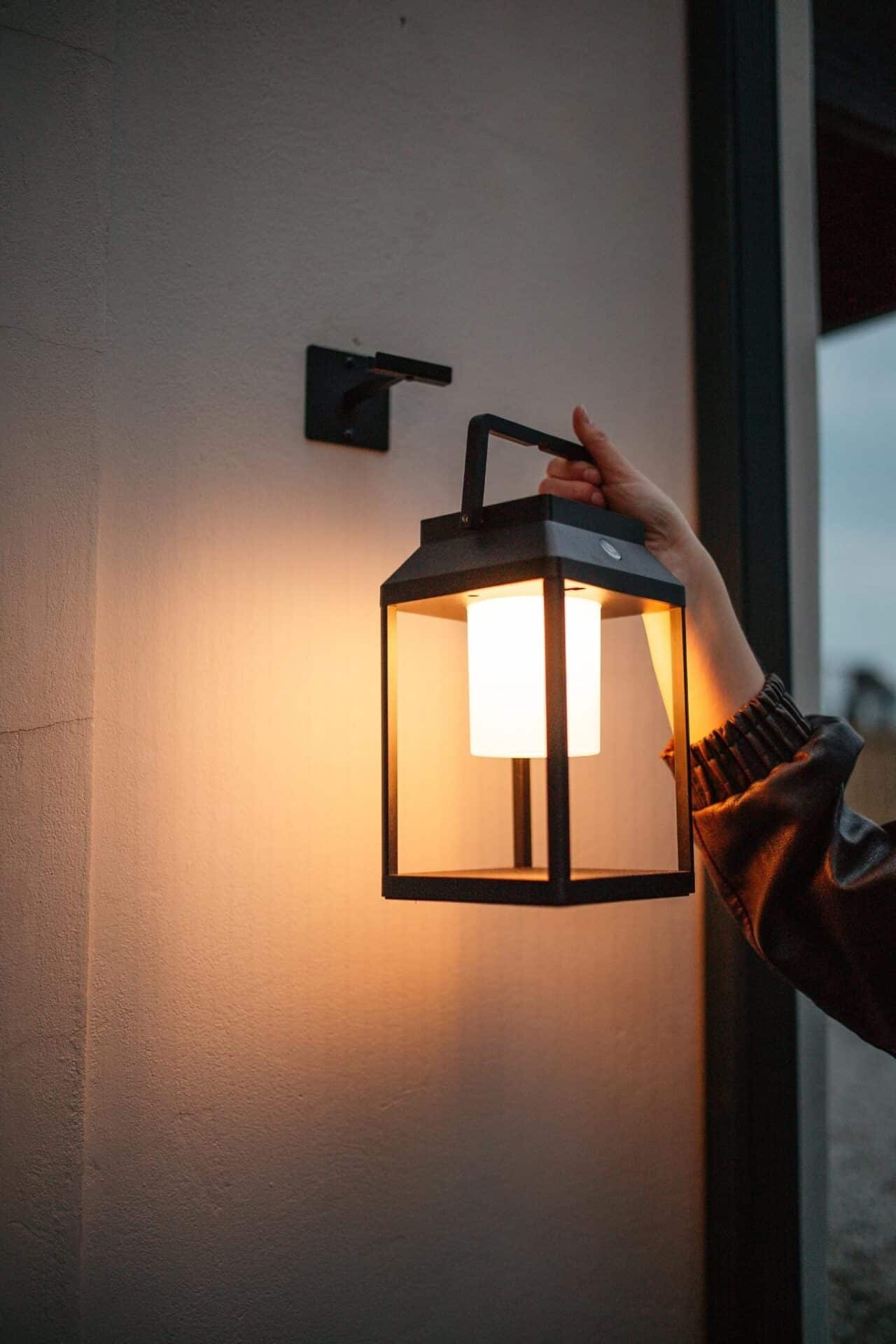 Black solar LED lantern mounted on outdoor wall with soft glow