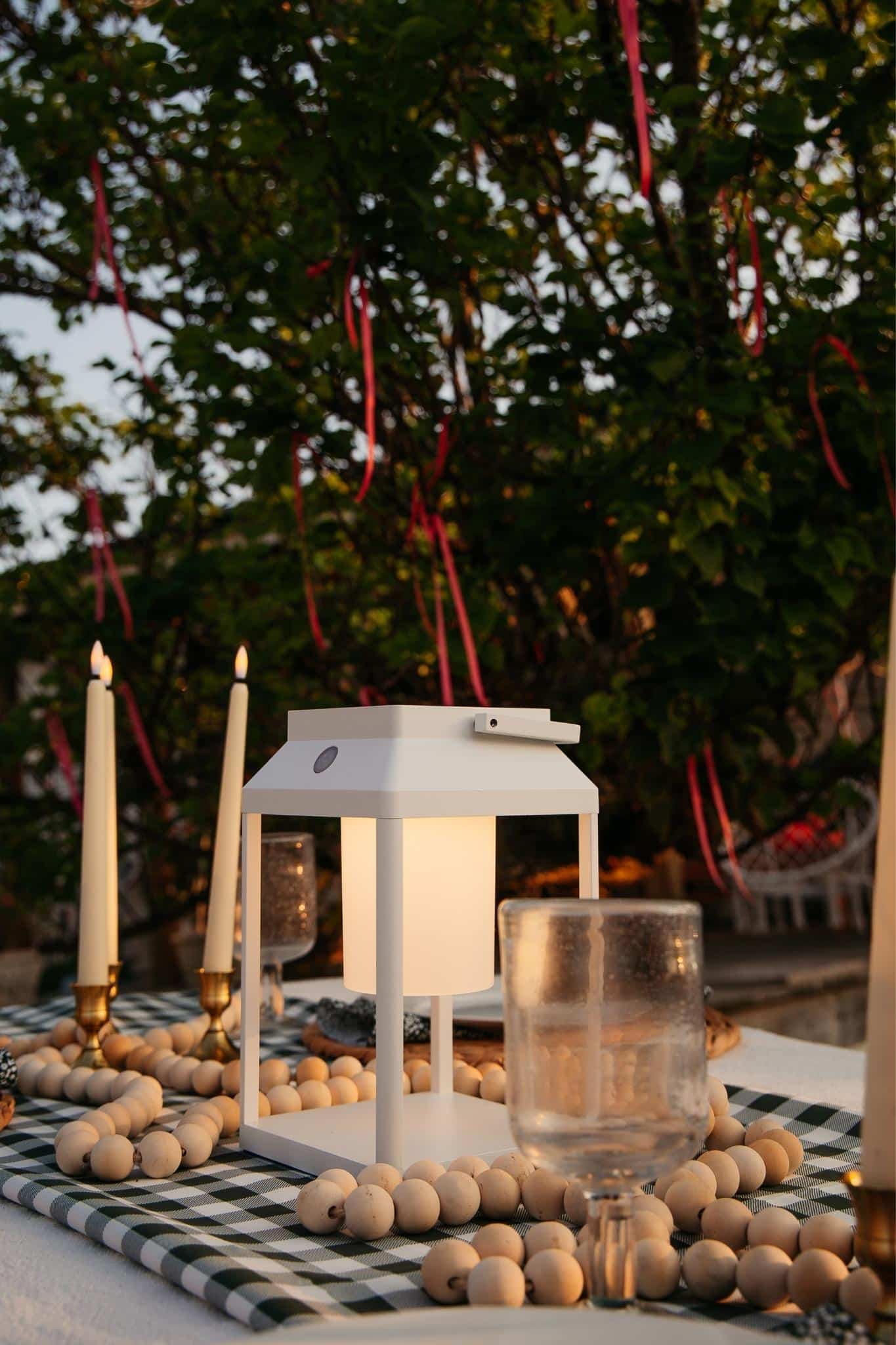 Portable white solar LED lantern on table and wall, warm light glow