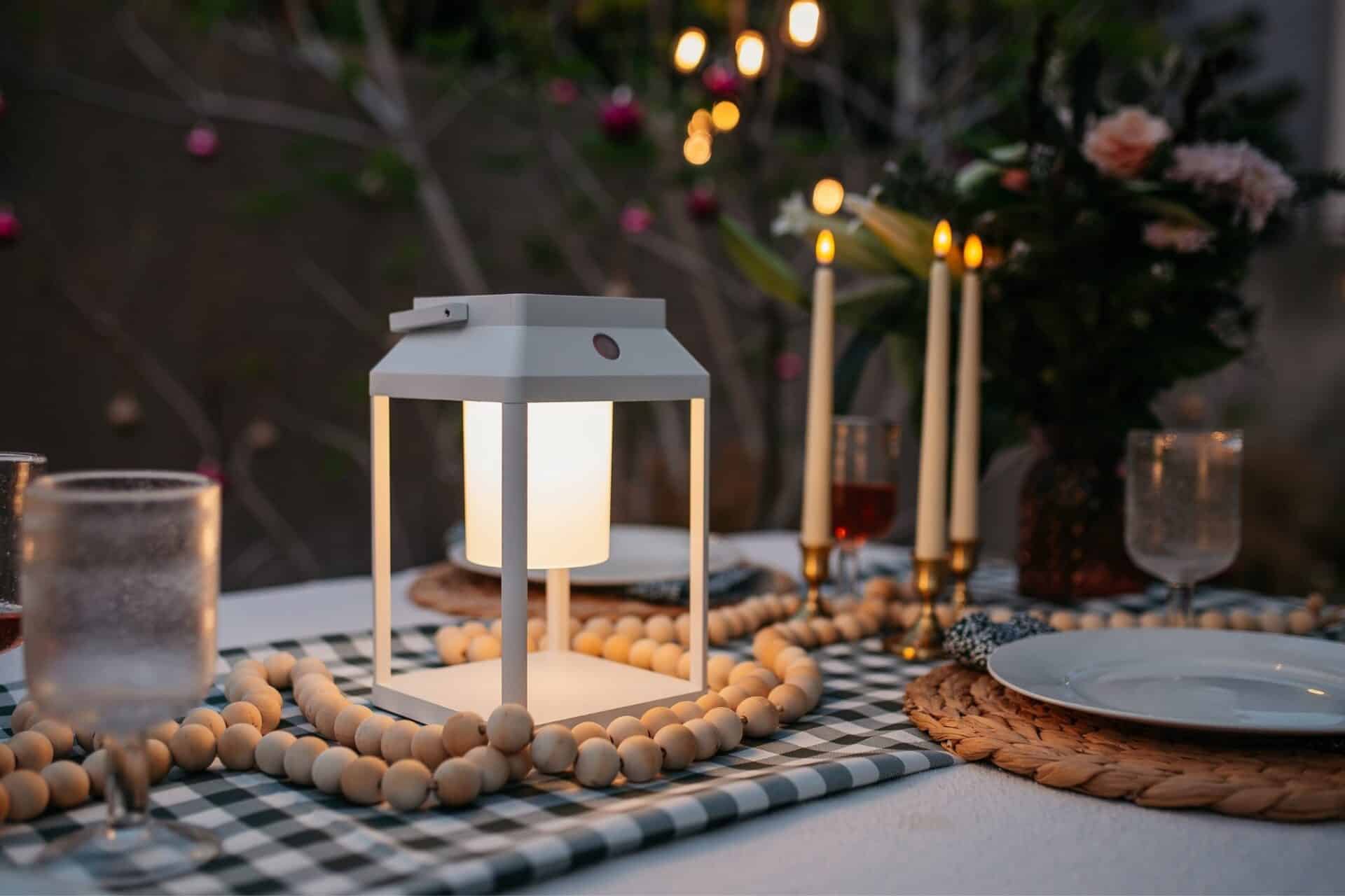 Portable white solar LED lantern on table and wall, warm light glow