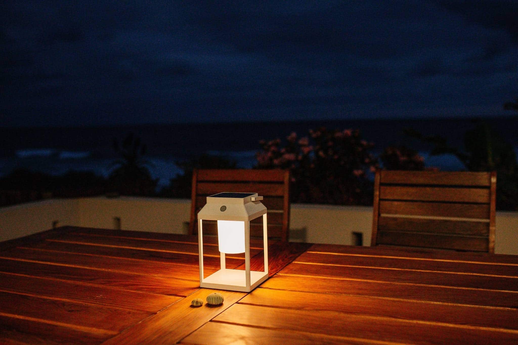 Portable white solar LED lantern on table and wall, warm light glow