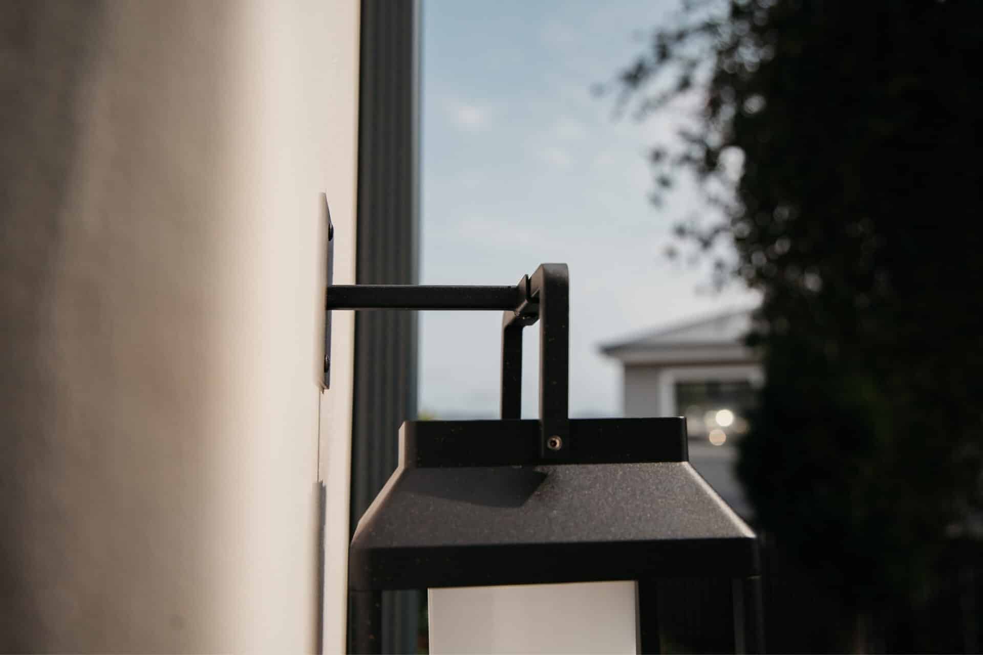 Black solar LED lantern mounted on outdoor wall with soft glow