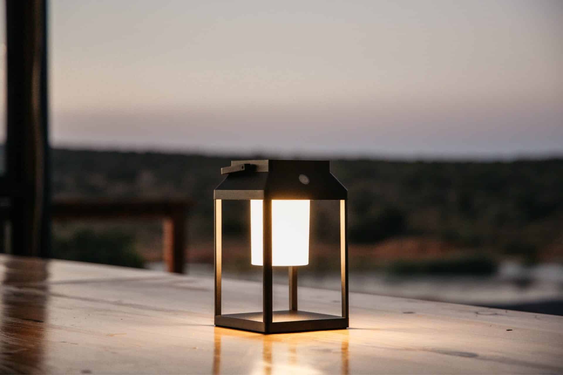 Black solar LED lantern mounted on outdoor wall with soft glow