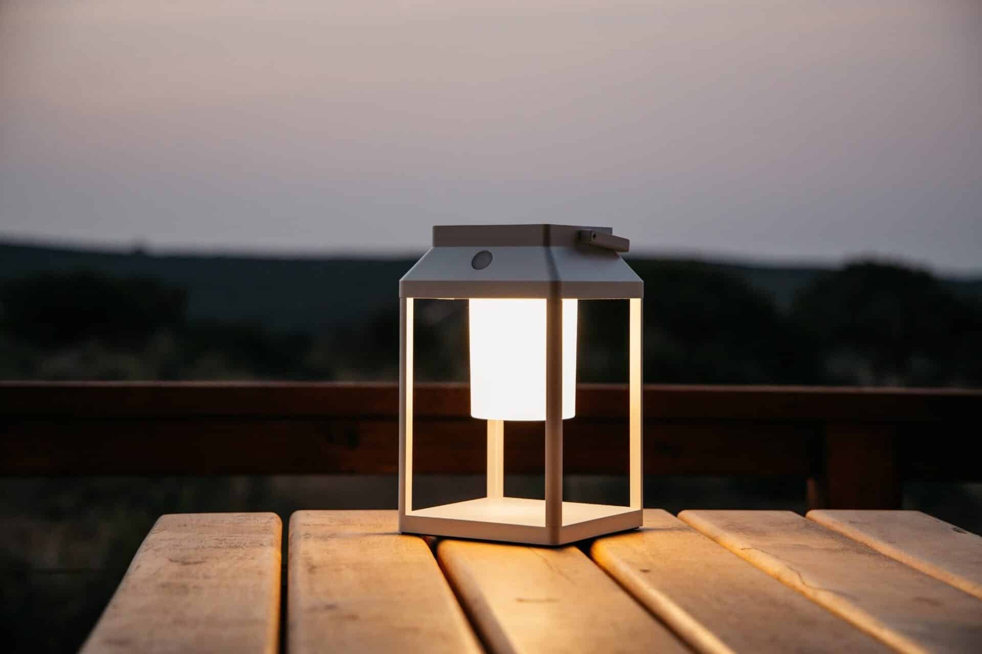 Portable white solar LED lantern on table and wall, warm light glow