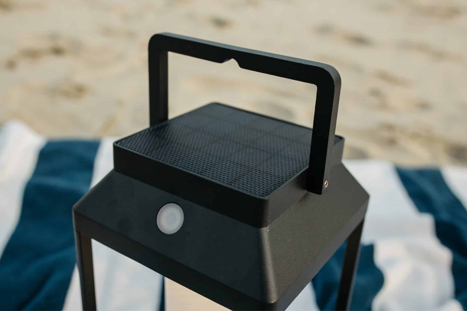 Black solar LED lantern mounted on outdoor wall with soft glow