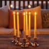Ivory flameless LED taper candles in holders glowing softly on a dining table.