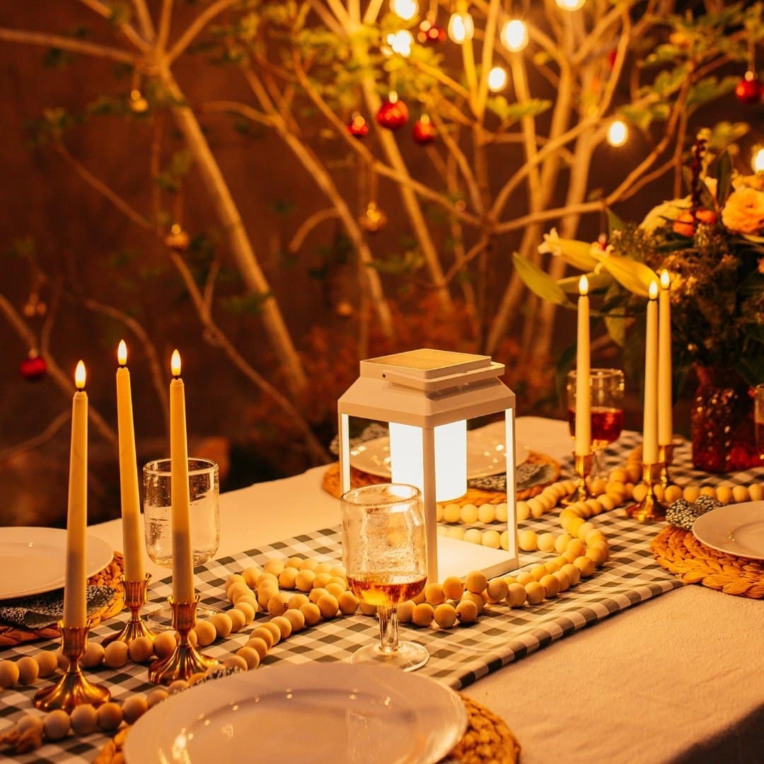 Ivory flameless LED taper candles in holders glowing softly on a dining table.