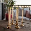 Ivory flameless LED taper candles in holders glowing softly on a dining table.