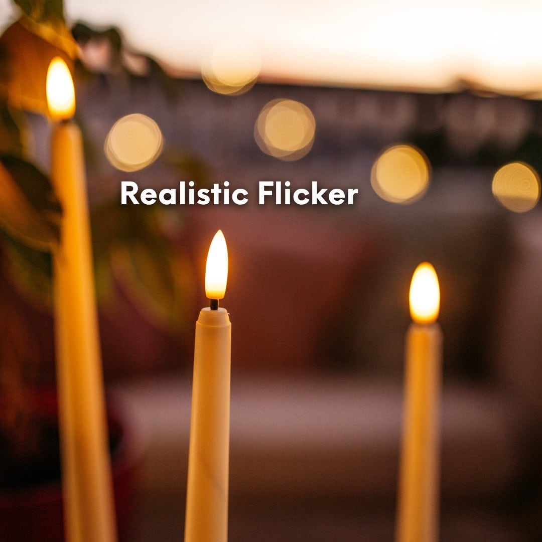 Ivory flameless LED taper candles in holders glowing softly on a dining table.