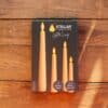 Ivory flameless LED taper candles in holders glowing softly on a dining table.