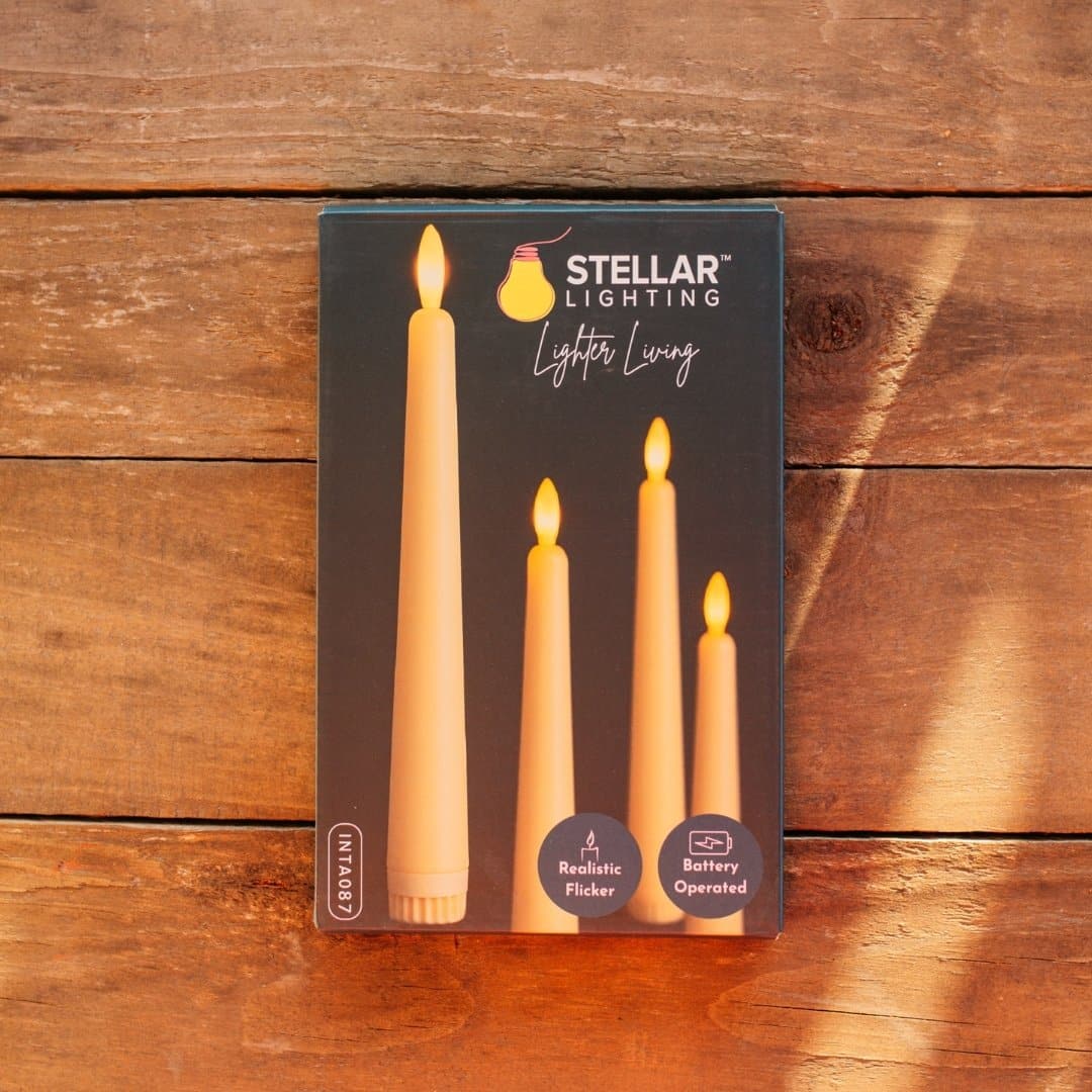 Ivory flameless LED taper candles in holders glowing softly on a dining table.